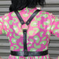 Person wearing a pink and green patterned dress with black harness.