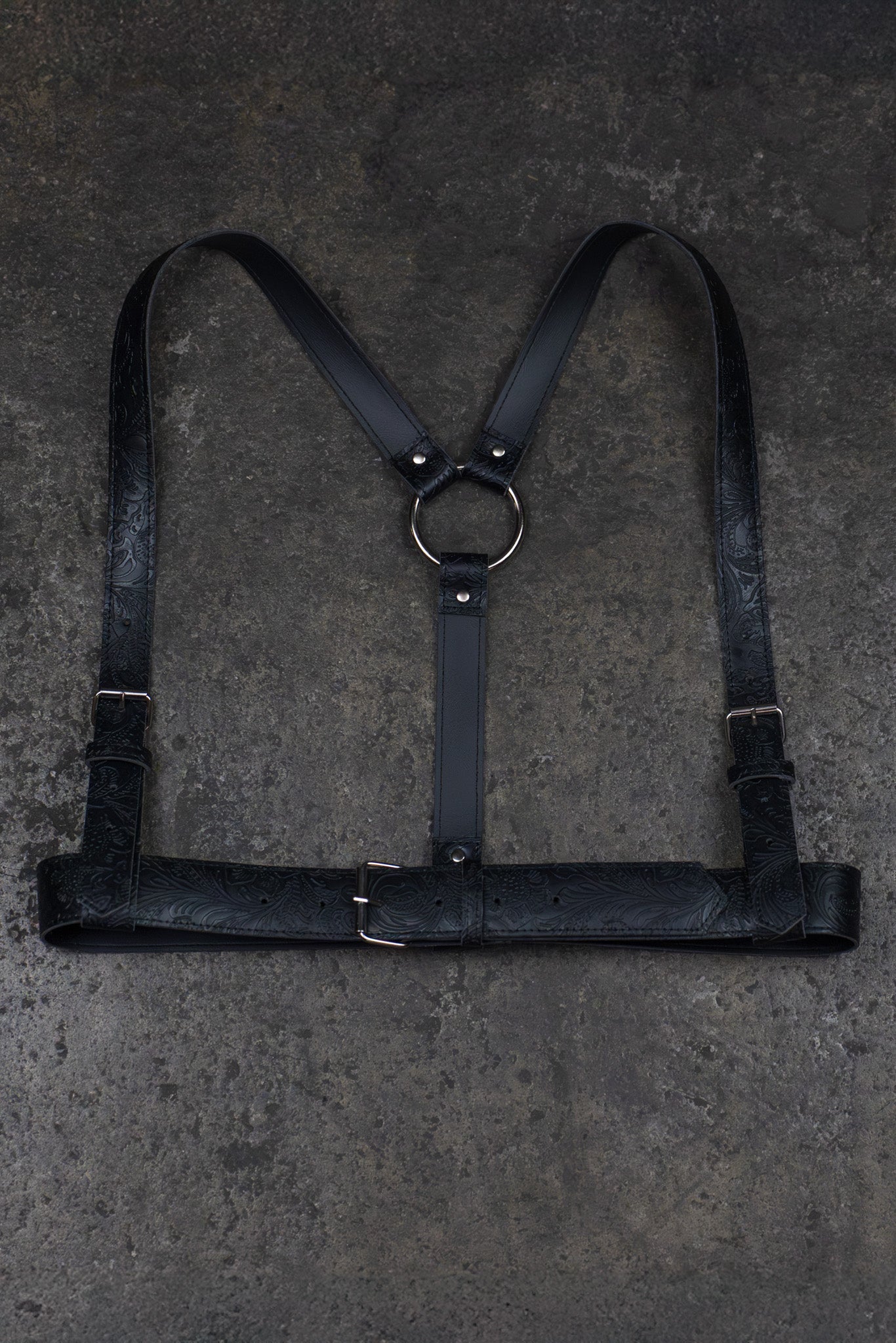 Black leather harness on a textured gray surface