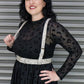 Woman wearing a black dress with a leopard print pattern and white harness against a metallic background.