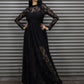 Woman wearing a black lace dress standing against a metal shutter.