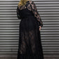 Woman wearing a black lace dress standing against a metallic shutter.