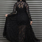 Person wearing a black lace dress standing in front of a metal shutter.