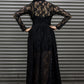 Person wearing a long black lace dress against a metallic shutter background.