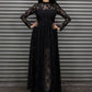 Woman wearing a black lace dress standing in front of a metal shutter.