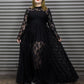 Person wearing a black lace dress standing in front of a metallic shutter.