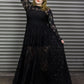 Person wearing a black lace dress against a metal shutter background.