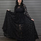Person wearing a black lace dress standing against a metallic shutter.