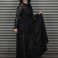 Person wearing a long black lace dress against a metal shutter background.