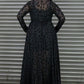 Person wearing a black dress with a leopard print pattern against a metal shutter background