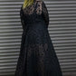 Person wearing a black leopard dress against a metallic background