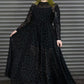Person wearing a black dress with long sleeves and a pattern against a metallic background