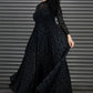 Woman wearing a black dress with a pattern in front of a metallic shutter.