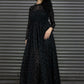 Woman wearing a black dress with a pattern against a metallic background