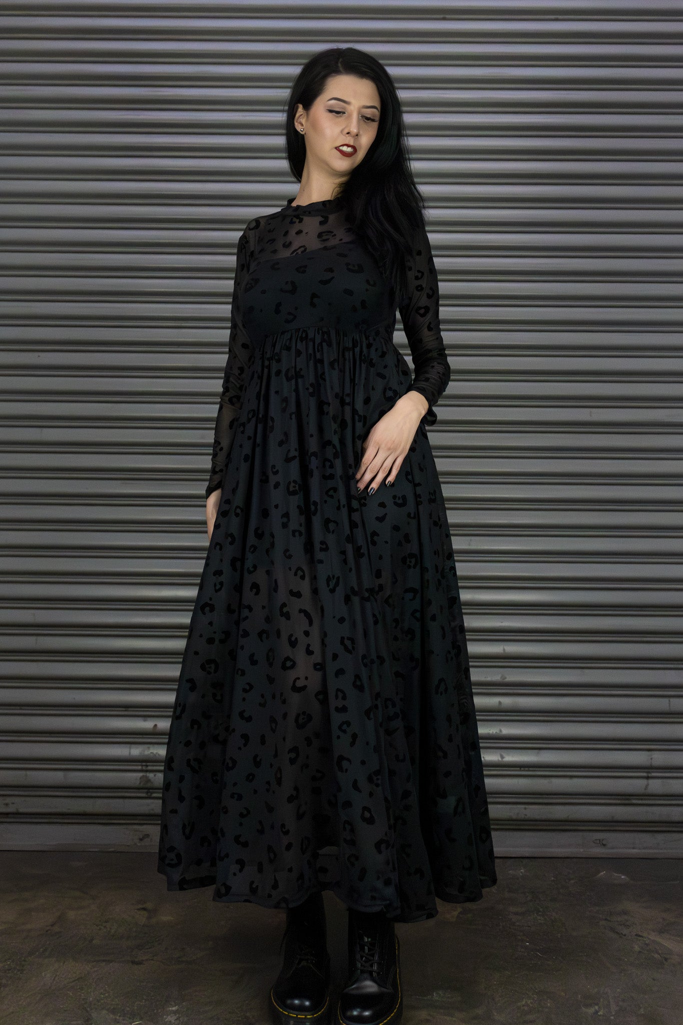 Woman wearing a black dress with a pattern against a metallic background