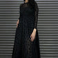 Woman wearing a black dress with a pattern against a metallic shutter background
