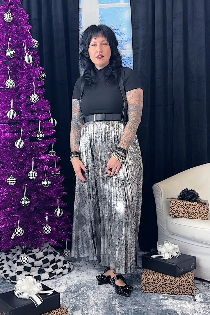 Person standing in a festive room with a purple Christmas tree and gift boxes.