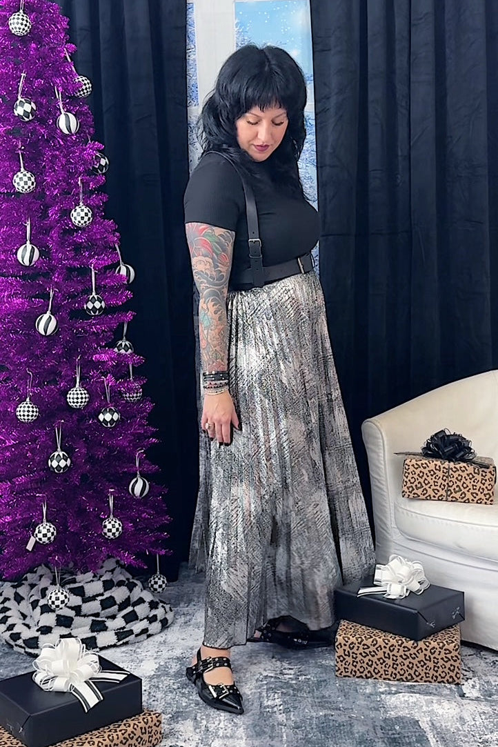 Woman standing in a room with a purple Christmas tree, gifts, and a white couch.