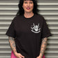 Woman wearing a black t-shirt with a white graphic design in front of a metallic shutter.