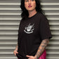 Woman wearing a black t-shirt with a graphic design in front of a metallic shutter.