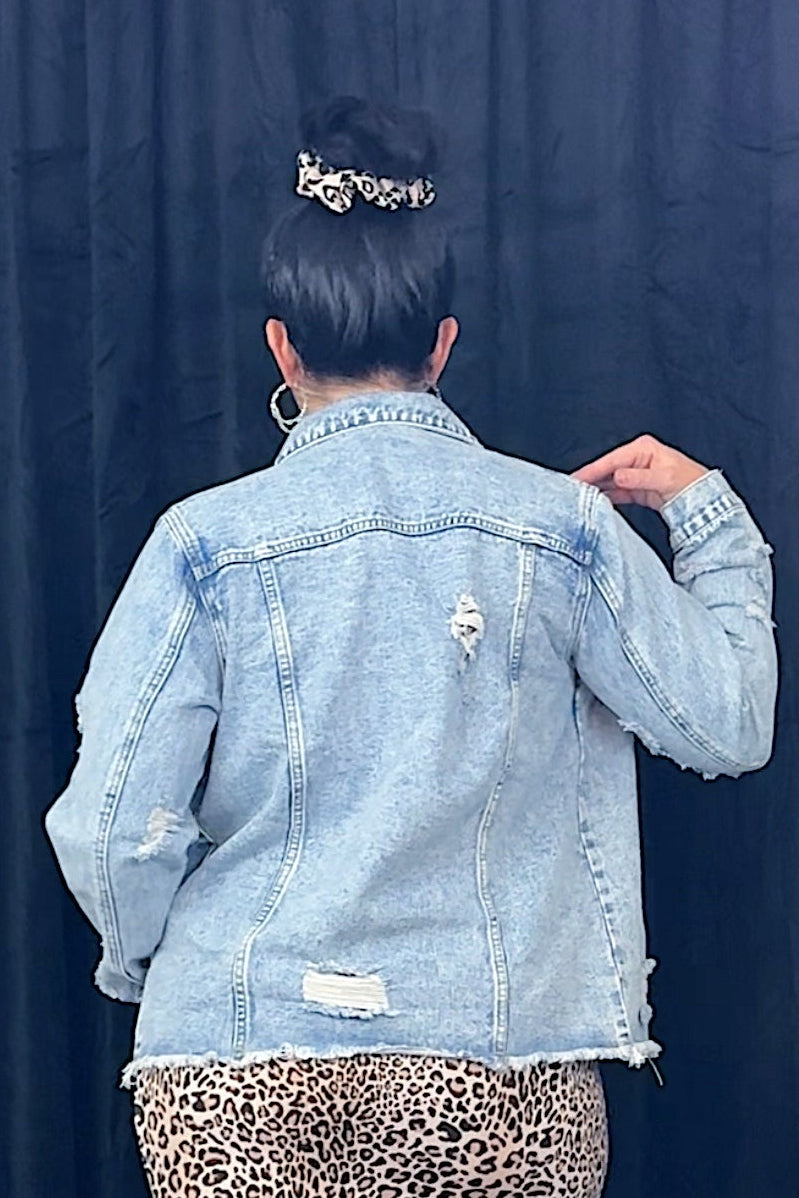 Person wearing a light blue denim jacket and leopard print skirt against a dark background