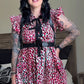 Person wearing a floral dress with suspenders in a bedroom setting