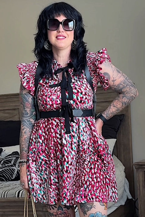 Person wearing a floral dress with suspenders in a bedroom setting