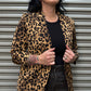 Woman wearing a leopard print jacket in front of a metal shutter.