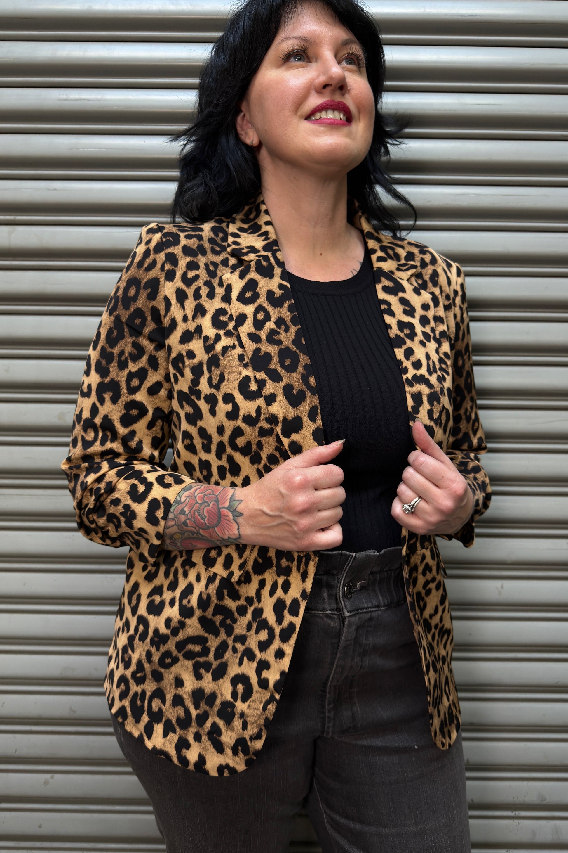 Woman wearing a leopard print jacket in front of a metal shutter.