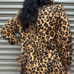 Person wearing a leopard print jacket standing in front of a metallic shutter.