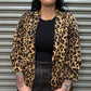Person wearing a leopard print jacket in front of a metal shutter.