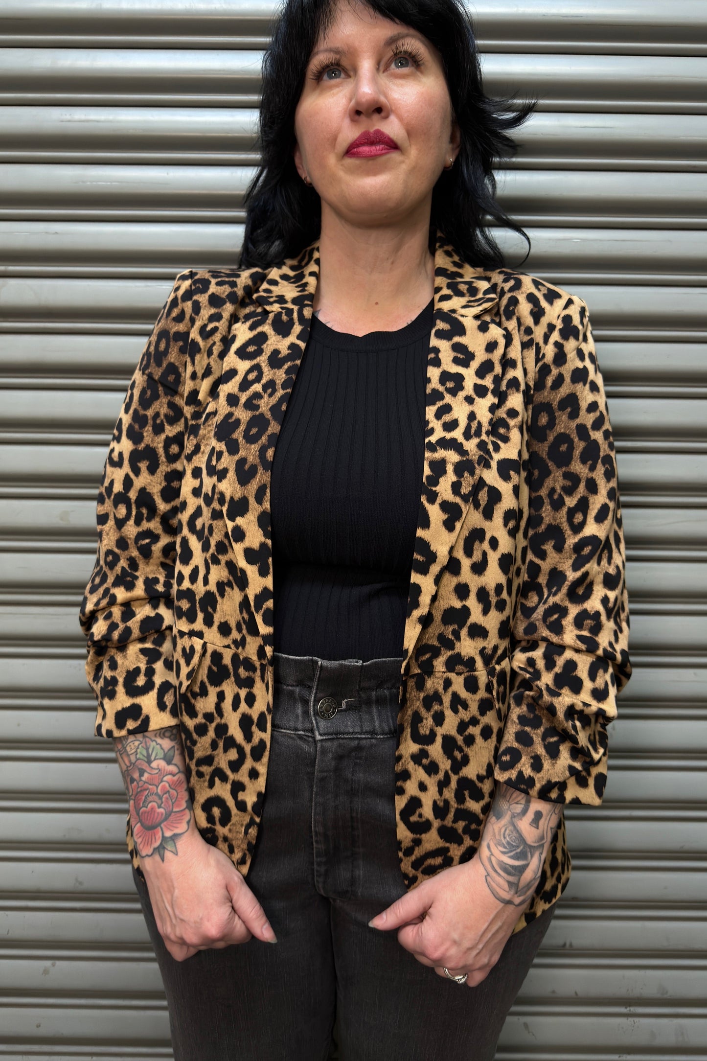 Person wearing a leopard print jacket in front of a metal shutter.