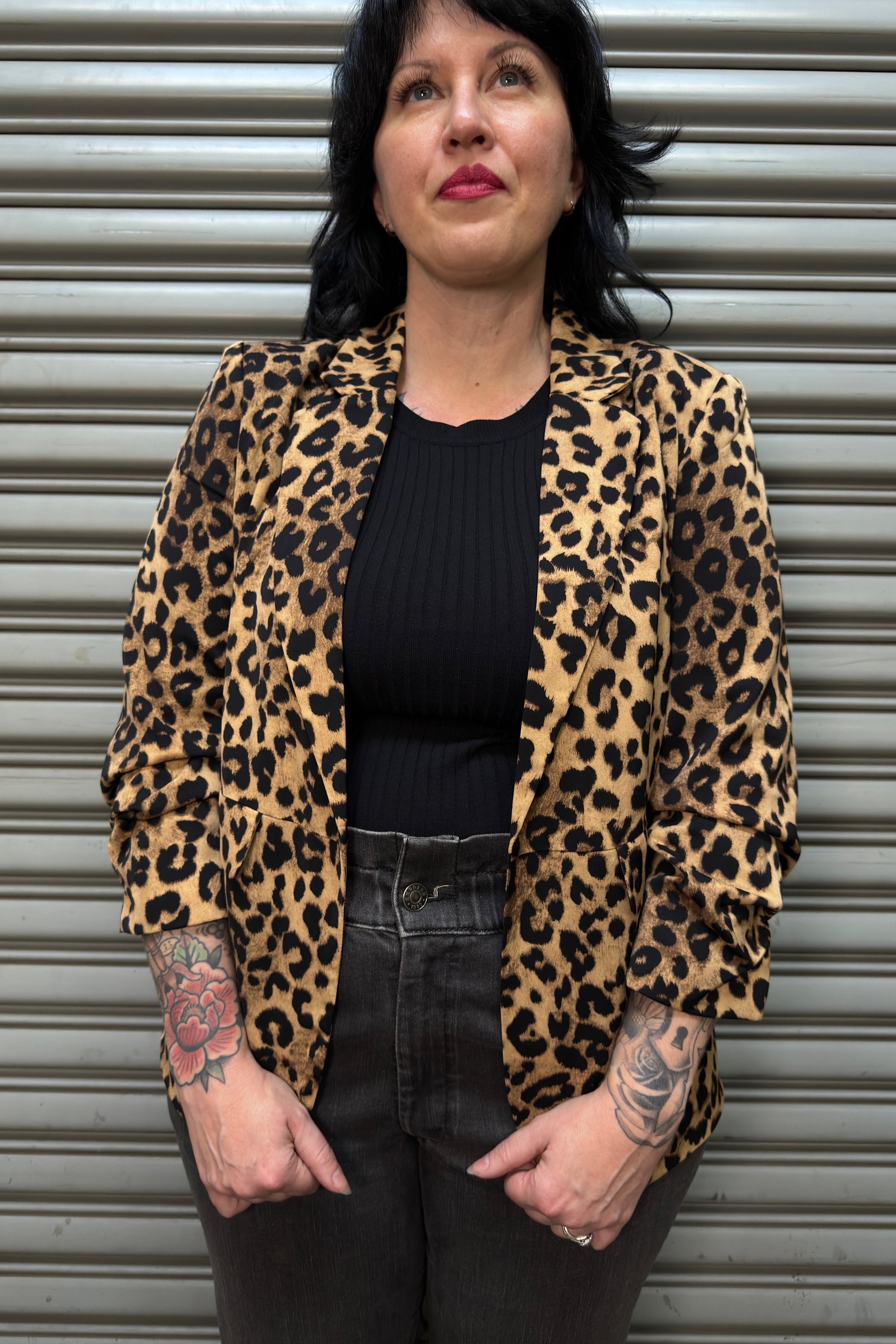 Person wearing a leopard print jacket in front of a metal shutter.