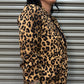 Person wearing a leopard print jacket standing against a metallic shutter.