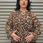 Women modeling leopard print top.