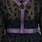 Purple harness with a gold ring on a black dress with leopard print details.