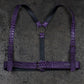 Purple leather harness with crocodile texture on a dark gray background