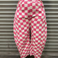 Person wearing pink and white checkered pants standing in front of a metal shutter.