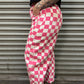Person wearing pink and white checkered pants standing in front of a metal shutter.