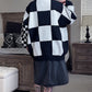 Person wearing a black and white checkered sweater in a bedroom setting