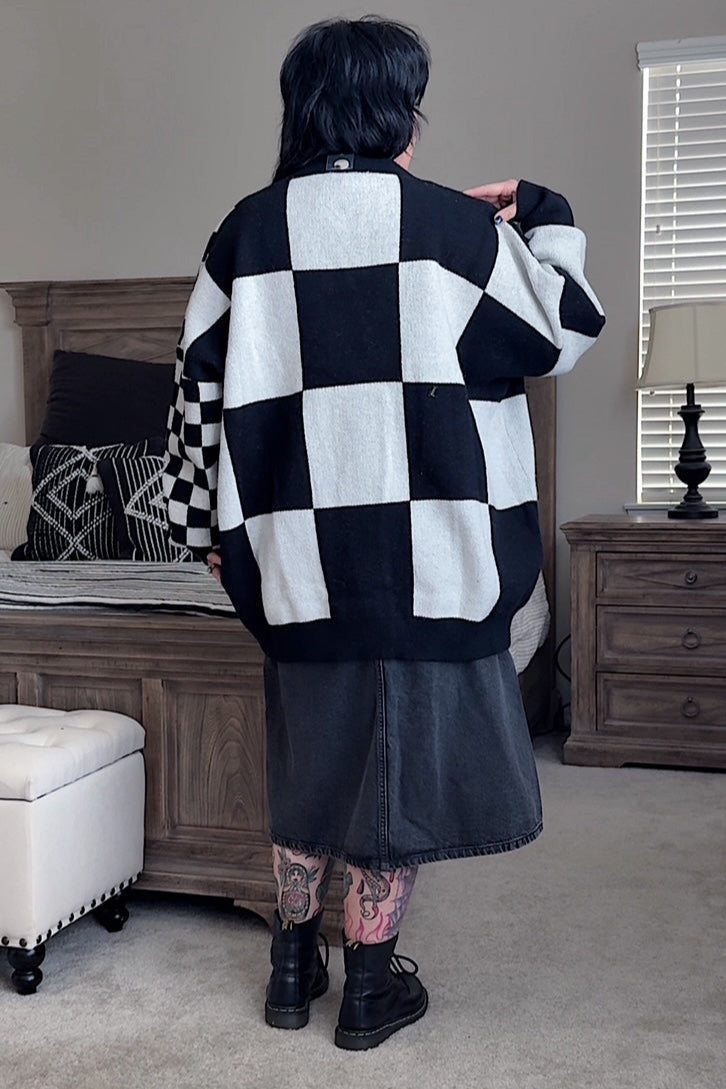 Person wearing a black and white checkered sweater in a bedroom setting