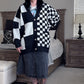 Person wearing a black and white checkered cardigan in a bedroom setting