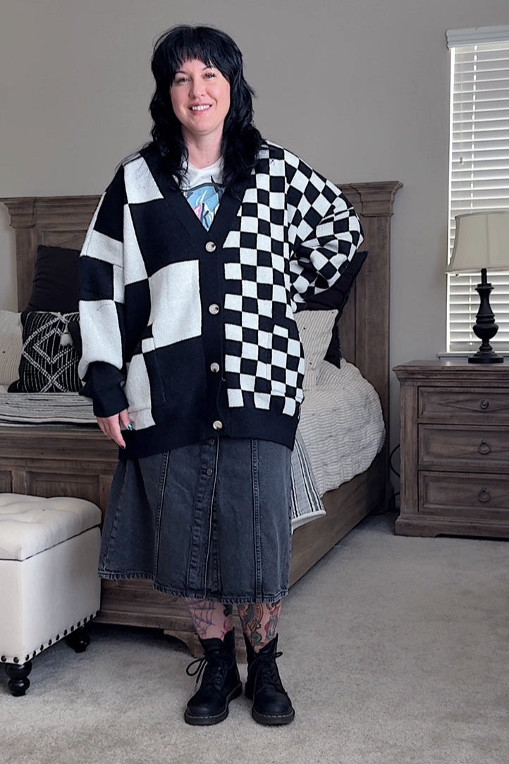 Person wearing a black and white checkered cardigan in a bedroom setting