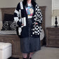 Person wearing a black and white checkered cardigan in a bedroom setting
