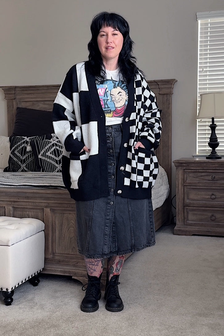 Person wearing a black and white checkered cardigan in a bedroom setting