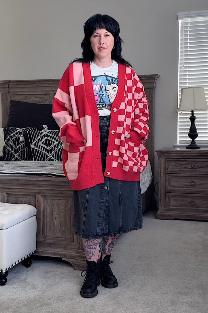 Person wearing a red checkered cardigan over a graphic t-shirt in a living room.