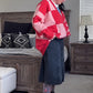 Person wearing a red and pink patterned cardigan in a bedroom setting