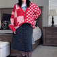 Person wearing a red and pink checkered cardigan in a bedroom setting