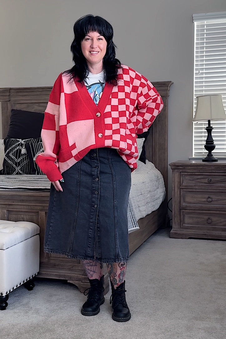 Person wearing a red and pink checkered cardigan in a bedroom setting