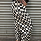 Person wearing black and white checkered pants standing in front of a metal shutter.