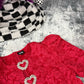 Red lace bodysuit with heart-shaped embellishments on a textured surface